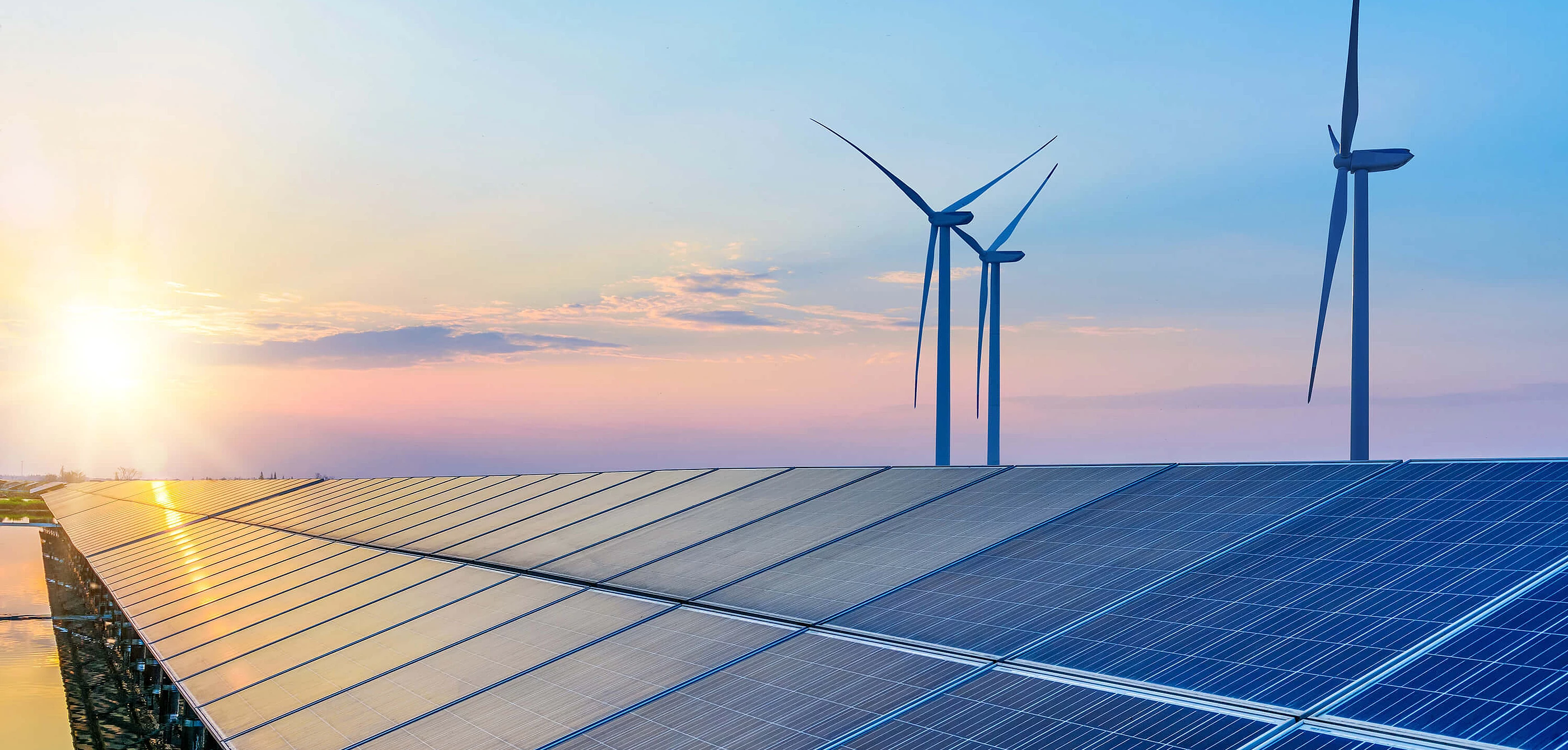 Solarpanele mit Windrädern und Sonnenuntergang im Hintergrund